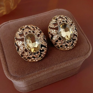 Close-up of vintage gold leaf earrings with champagne stones in a brown velvet box