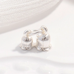 Close-up of a pair of small silver-colored lily of the valley bell-shaped jewelry charms