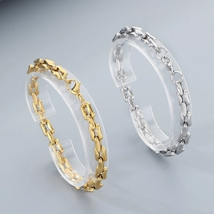 Polished gold and silver titanium steel chain bracelets displayed on acrylic stands
