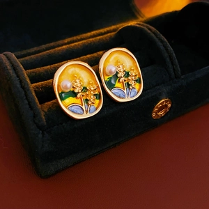 Detail of vintage gold-rimmed enamel wheat earrings with pearls in a black velvet box