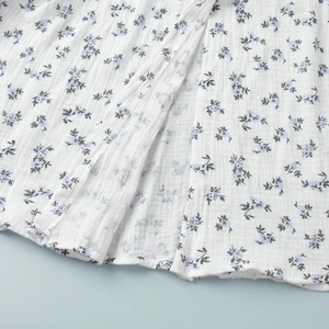 Detail of floral print on breathable muslin cotton fabric with slit hem and fine stitching
