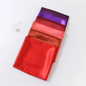 Detail of multi-color 90cm satin square scarves neatly folded in gradient red and purple hues