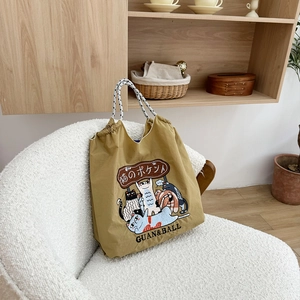 Detailed close-up of khaki nylon tote bag featuring colorful cartoon cat embroidery