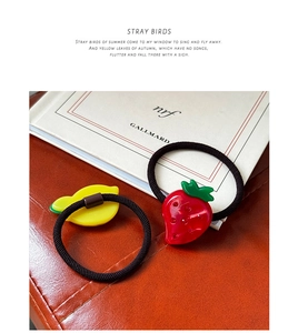 Detail of strawberry and lemon acetate charms on high-elasticity hair ties