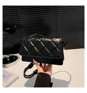 Gros plan du sac à bandoulière en cuir noir matelassé avec des détails dorés