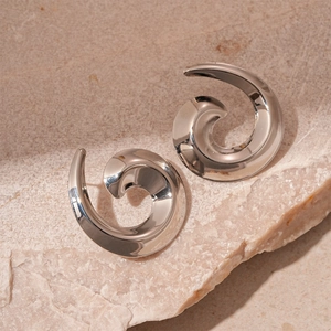 Detailed view of silver spiral stud earrings on a textured stone background