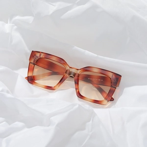 Retro amber square oversized sunglasses on white pleated fabric background