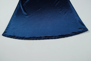 Detailed view of the smooth dark blue satin fabric and hem stitching on the dress