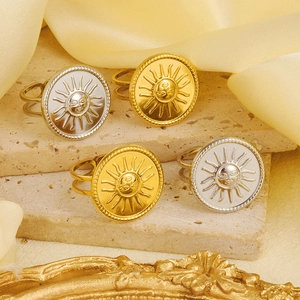 Detail of sun face relief rings in gold and silver finish on textured stone