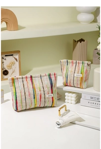 Détail de deux trousses de toilette tissées avec broderies verticales colorées et zip en métal