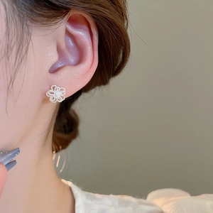 Close-up of a model wearing a silver hollow flower stud earring in minimalist design