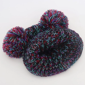 Detail of colorful knitted winter hat with double pom-poms on white background