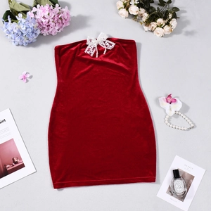 Detail of red velvet mini dress featuring a white lace bow and faux pearl pendant