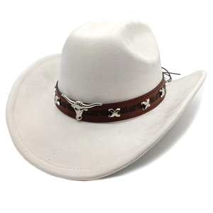 Detail of white suede cowboy hat featuring brown leather band and silver bull head emblem