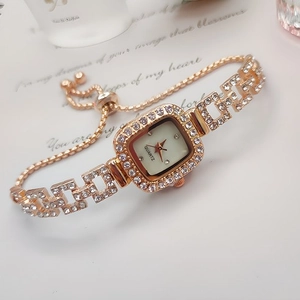 Detail of square gold watch featuring diamond bezel and adjustable sliding pull clasp