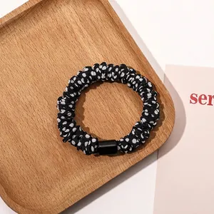 Close-up of black and white polka dot scrunchie with a black buckle on a wooden tray