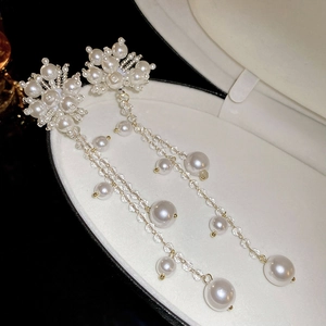 Close-up of floral pearl earrings with long crystal tassels in a jewelry box