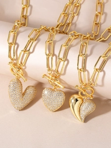 Three gold heart pendant necklaces with zircons and paperclip chains on silk fabric