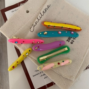 Macro detail of colorful acrylic hair clips with rhinestones on canvas fabric