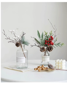 Close-up of Christmas sprigs with red berries and pine cones in a glass vase decor