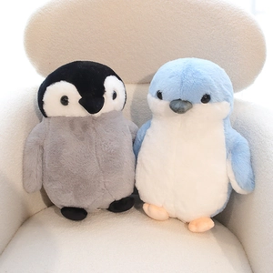 Soft and cuddly plush penguin dolls in grey and light blue sitting on a white chair
