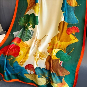 Elegant satin silk scarf with vibrant ginkgo leaf print and smooth draped texture