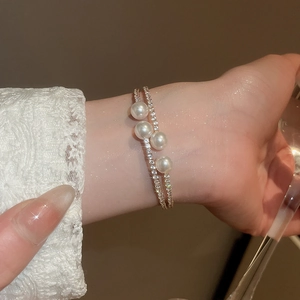 Détail d'un bracelet double couche en strass avec perles élégantes porté sur un poignet