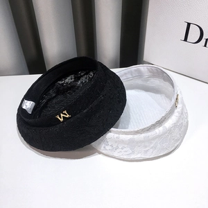Detail shot of black and white lace beret hats with gold M letter and floral texture