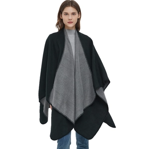 Double-sided black and grey knit shawl cape with stitched edges on a model in jeans