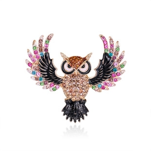 Macro shot of owl brooch featuring brown rhinestones and colorful enamel wings