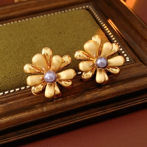 Macro detail of 18k gold plated flower earrings with purple bead on velvet surface