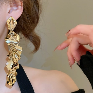 Close-up of model wearing gold layered metallic flower petal long tassel earrings