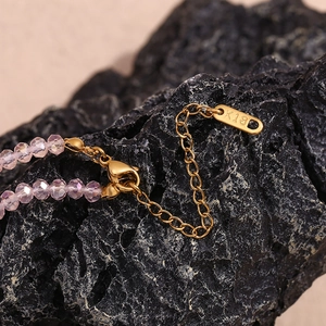 Detailed macro view of K18 engraved metal tag with pink crystal beads and stainless steel