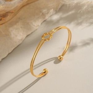 Elegant 18K gold plated stainless steel knot cuff bracelet with ball ends in a warm setting