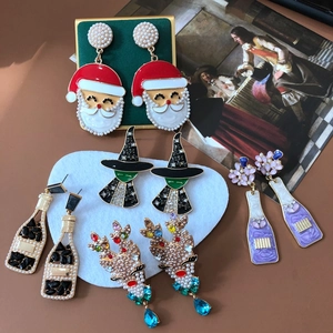 Detailed flat lay of Christmas earrings with Santa, elk, and enamel charms on velvet