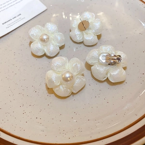 Detail view of fabric flower earrings with pearls and backings in a ceramic plate