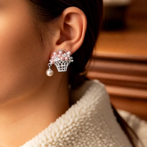 Gros plan détaillé d'une boucle d'oreille panier en argent avec perles roses et blanches