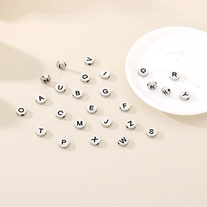 Macro shot of silver stainless steel round alphabet beads with black engraved letters A-Z