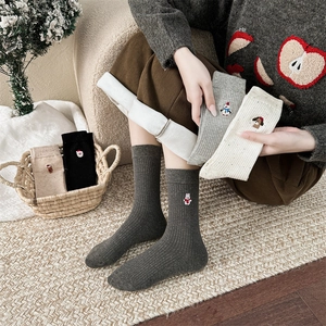 Détail de chaussettes de Noël tricotées avec broderie cartoon et texture côtelée