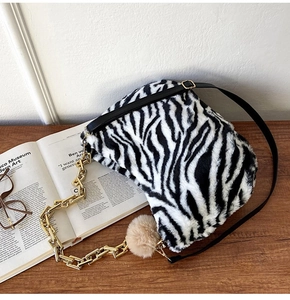 Detailed shot of plush zebra print handbag with chunky gold chain and furry charm