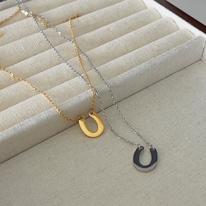 Minimalist U-shaped horseshoe pendant necklaces in gold and silver finish on display