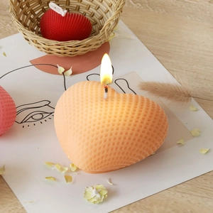 Dettaglio della candela a cuore intrecciata con trama a nido d'ape e luce calda