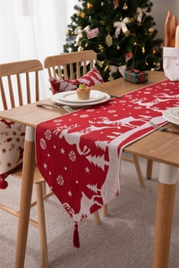 Dettaglio runner da tavola natalizio rosso con motivi di renne e nappe decorative