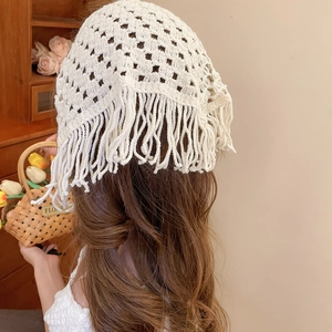 Detailed view of beige crochet hollow triangle scarf with tassels worn as a headscarf