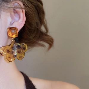 Gros plan de boucles d'oreilles pendantes feuille de ginkgo en écaille ambrée sur mannequin