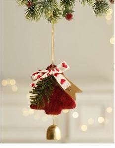 Detail of red plush Christmas tree ornament with pine needles, ribbon bow and gold bell