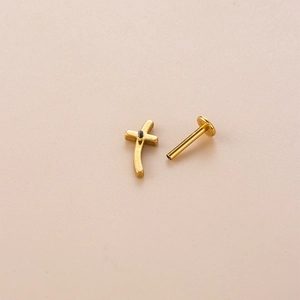 Macro shot of gold-plated cross stud earring with threaded flat back piercing detail