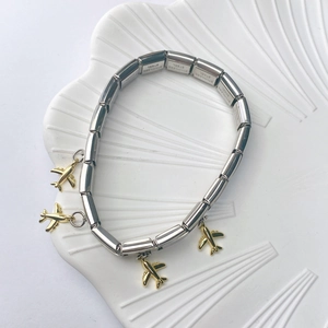 Detailed macro view of stainless steel charm bracelet with golden airplane pendants on shell