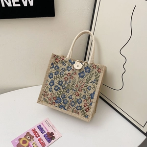 Detail of linen handbag featuring floral embroidery and round wooden buckle closure