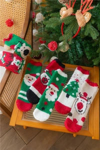 Détail de chaussettes de Noël en polaire corail avec motifs de Père Noël et de renne